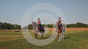 Two females equestrians riding horses at country racetrack