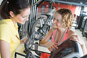 two females riding stationary bicycles in modern club for women