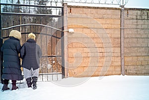 two females standing in front of the closed metal gates, winter scene