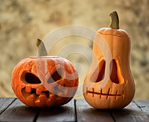 Two festive scary halloween pumpkins on a wooden table