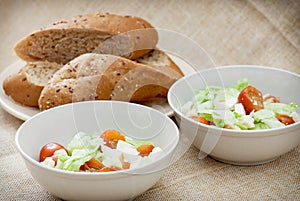 Two fetta salad portions and slices of bread photo