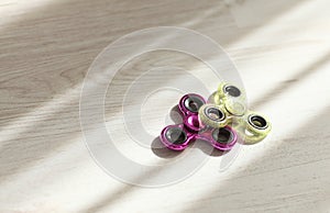 Two fidget spinners pink and green stress relieving toys closeup in sunlight