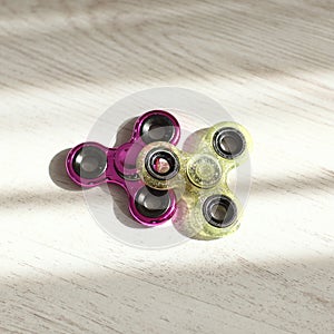 Two fidget spinners pink and green toys closeup in sunlight