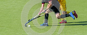 Two field hockey player, fighting for the ball on the midfield during an intense match on artificial grass