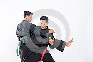 Two fighters in black pencak silat uniform fight in locks and slams