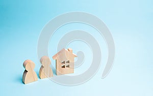 Two figures of people and a wooden house on a blue background. The concept of affordable housing and mortgages for buying a home photo