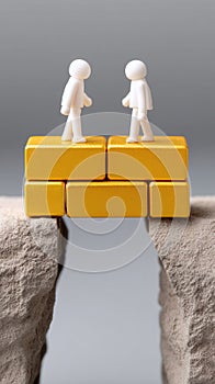 Two Figurines Standing on Blocks Over a Gap Representing Connection photo