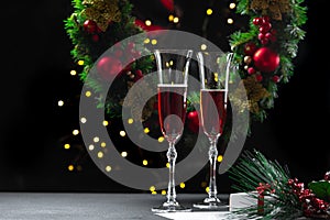 two filled champagne glasses against the background of a Christmas wreath