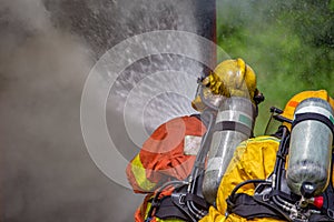Two firefighters water spray high pressure nozzle to fire and sm
