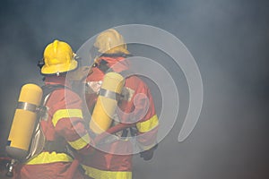 Two firefighters is working surround with smoke and dust