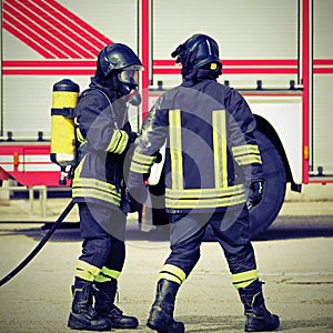 two firemen with uniform and helmet during an emergency