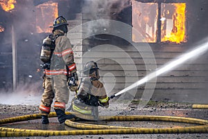 Two Firemen working with water hoses