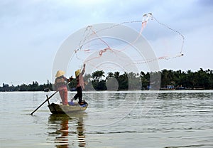 Two fishermen in action in a little boat
