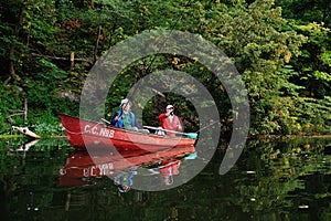 Two fishermen in a boat with fishing rods catching fish