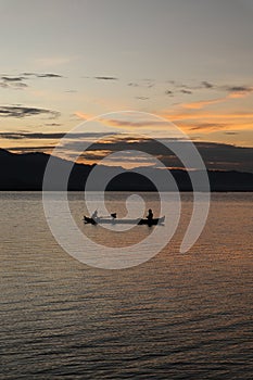 two fishermen on the lake from a boat at sunset. Limboto Lake, Gorontalo, Indonesia. beautiful sky in the afternoon