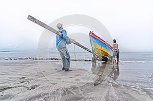 Two fishermen pull the boat