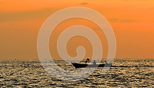 Two fishermen Take a small fishing boat to the sea at sunset