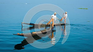 Two fishermen on traditional boats turning. Inle Lake, Myanmar