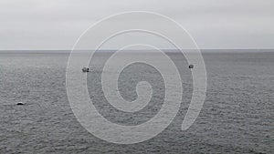 Two fishing boats anchored offshore on gray sea