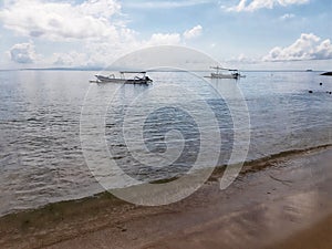 Two fishing boats floating on the water in open public area known as Sanur Beach