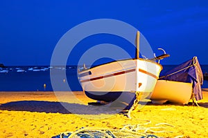 Two fishing boats on a sandy beach in the evening against the background of the sea.