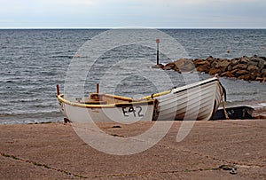Two fishing boats tied up on the shingle beach at Sidmouth in Devon, England