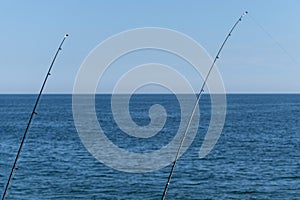 Two fishing rod against blue ocean or sea background, copy space. Waiting for biggest haul. Meditative relax sport