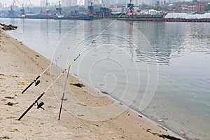 Two fishing roda on holders on river bank on cloudy autumn day