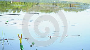 Two fishing rods on the lake in summer day. Professional fishing rod waiting for bites on water river