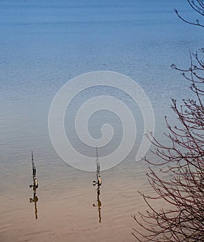 Two fishing rods at the side of a lake