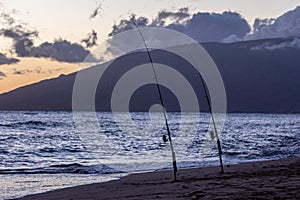 Two fishing rods stuck into a sand on of Kamaole II beach, Kihei, Maui, Hawaii.