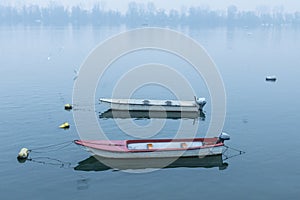 Two fishing and rowing boats on Zemun Quay Zemunski kej on a foggy dusk in winter over the Danube river, Belgrade in Serbia