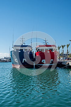 Two fishing trawlers, one blue and one red.