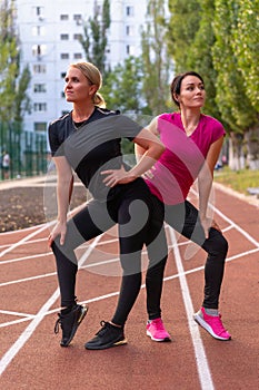 Two fit athletic women posing hip to hip