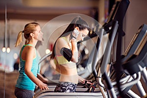 Two fit women running on treadmills in modern gym