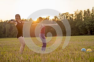 Two fit young women working out with dumbbells standing in the m