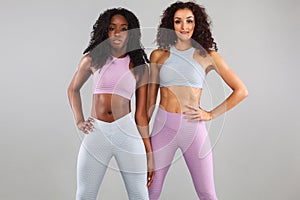 Two fitness women in sportswear isolated over gray background. Sport and fashion concept with copy space.