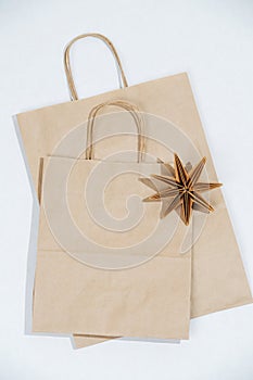 Two flat paper bags with rope handles and origami star on a white surface.