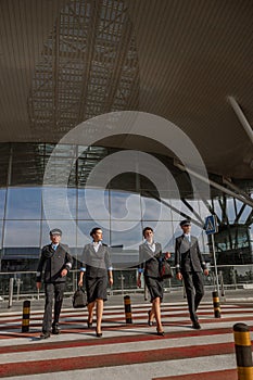 Two flight attendants with bags walking next to the pilots outdoor