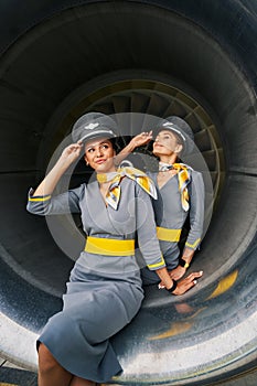 Two flight attendants in pilot caps seated in the aeroengine