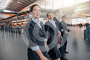 Two flight attendants and pilots walking through the terminal to the plane