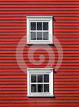 Two floors of windows on a red wooden facade