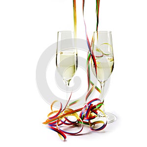 Two flute champagne glasses with colorful paper streamers on white