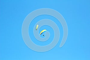 Two paragliders in blue sky