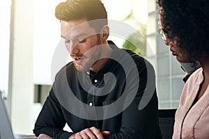 Two focused businesspeople talking together at an office desk