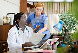 Two focused doctors discussing medical histories of patients