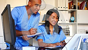 Two focused doctors working with patient records on laptop in modern medical office