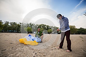 Two focused men lay out a kite, paraglider