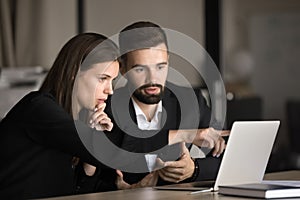 Two focused young business colleagues working at laptop