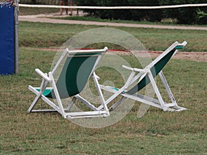 two folding chairs on a lawn of green grass without people